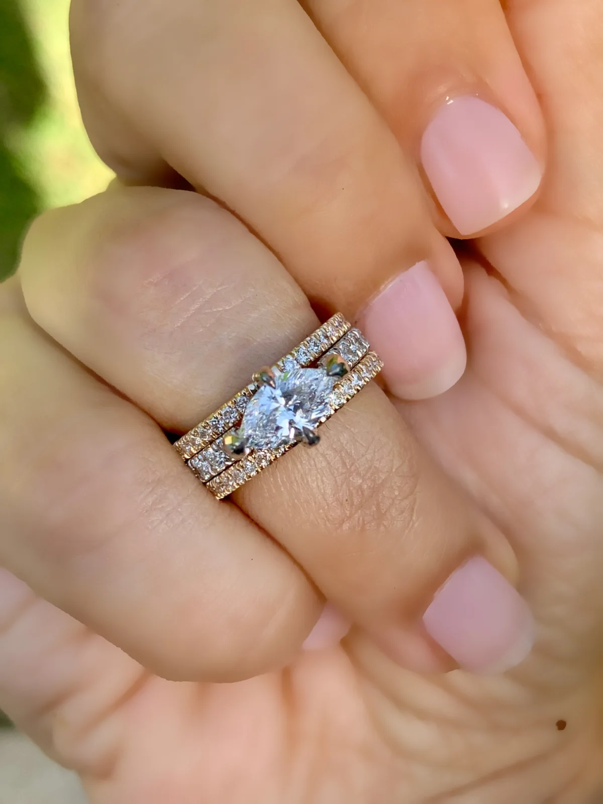 A marquise diamond ring stacked between two diamond bands, worn on a hand