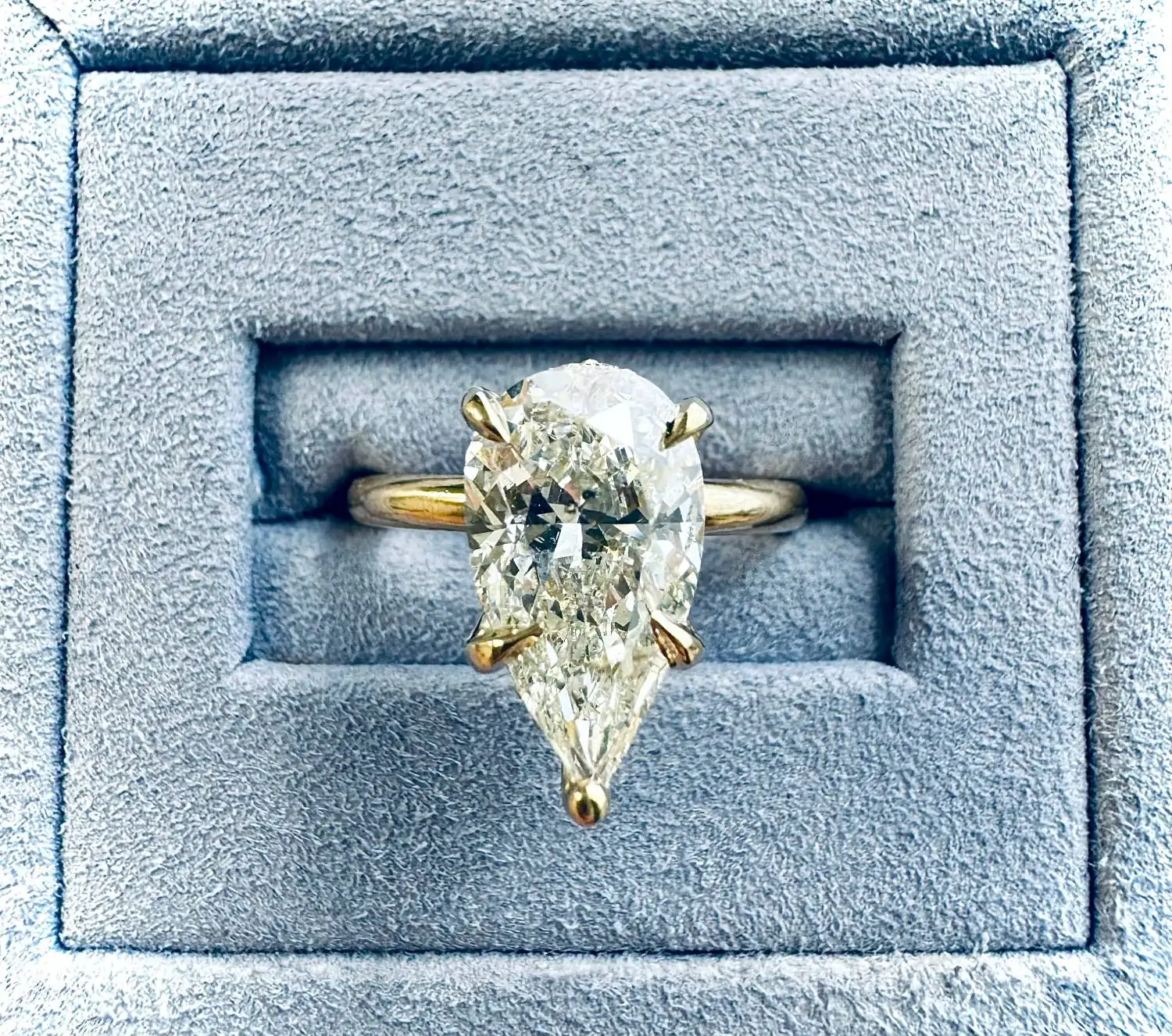A pear-shaped diamond solitaire in a blue suede ring box