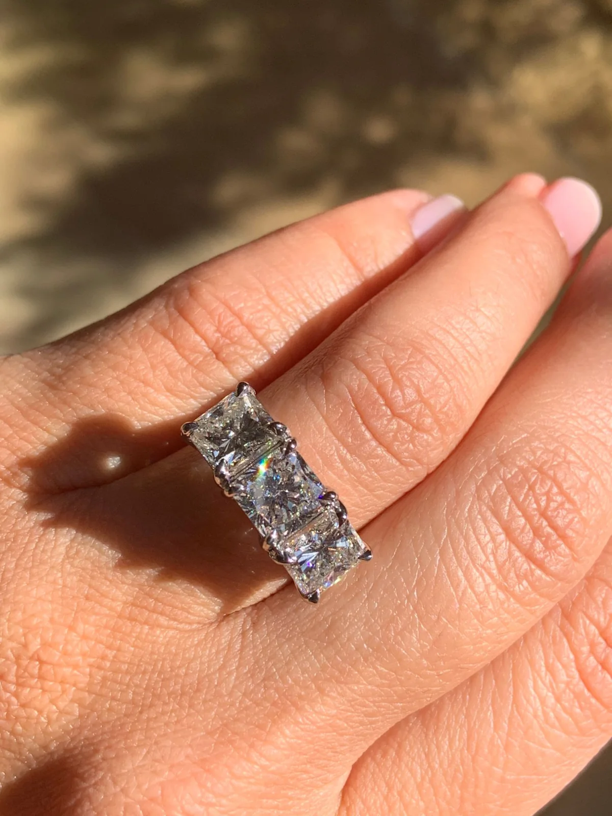 Princess-cut three-stone ring worn in sunlight