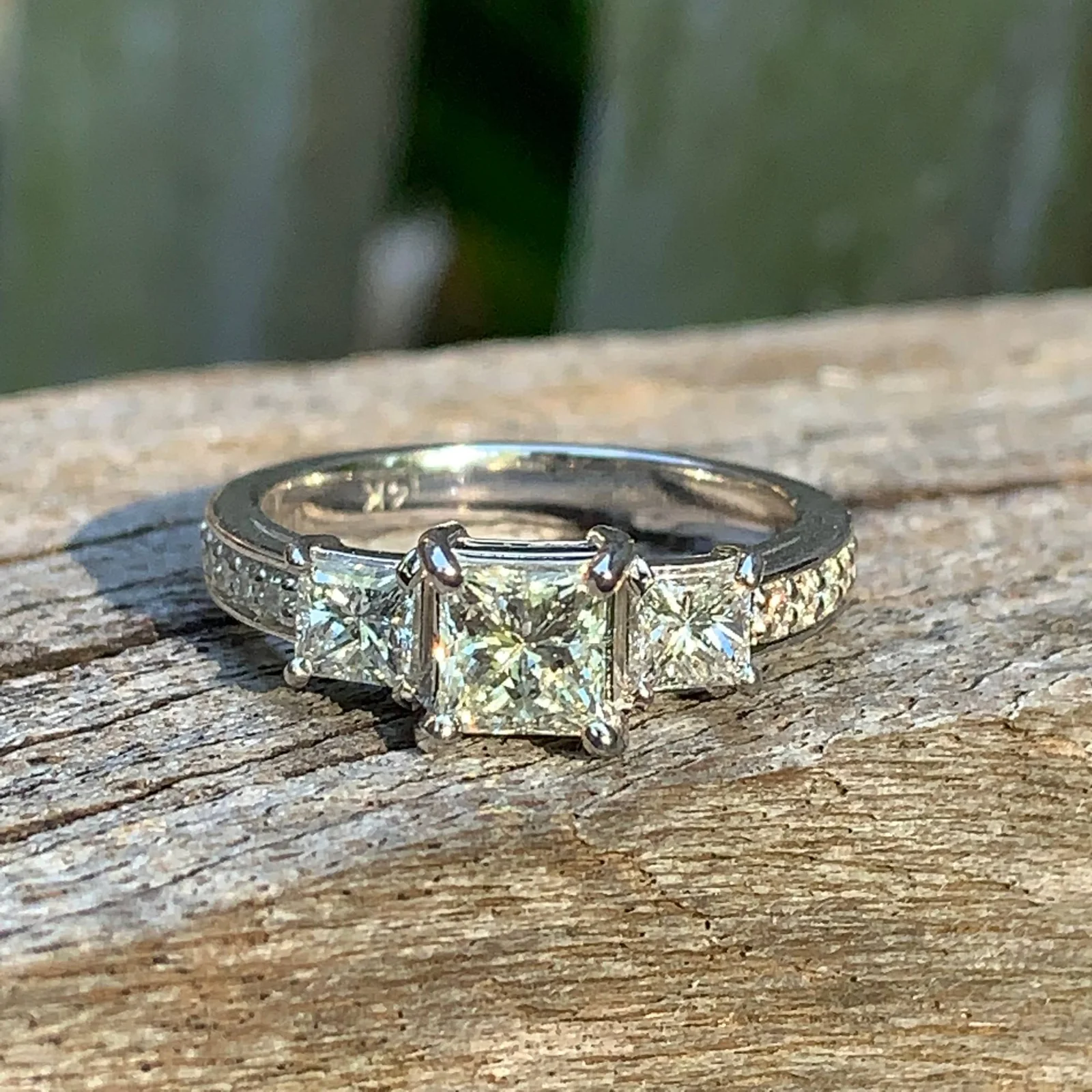 Princess-cut three-stone ring in white gold on wood