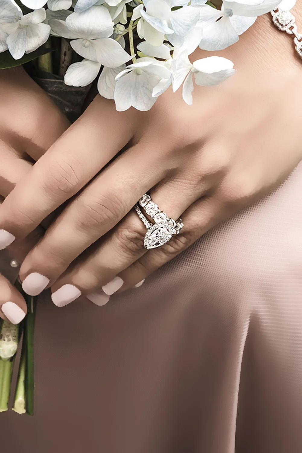 Hands holding white flowers, wearing a diamond engagement ring and band